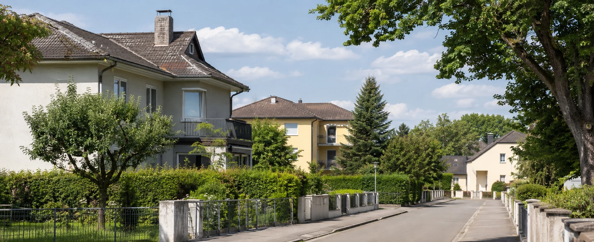 Gewöhnliche Wohnstraße mit Häusern, Gärten und Mehrfamilienhaus